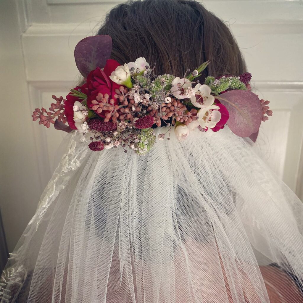 Brudehåropsætning med røde, lilla og lyserøde blomster