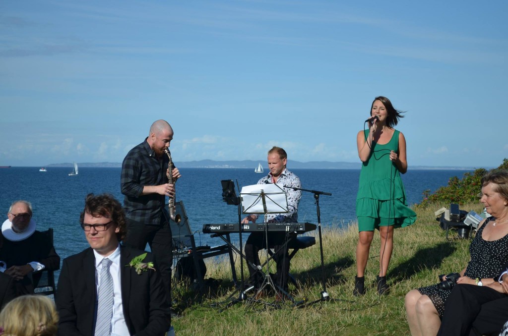 Bryllups sanger med pianist og Klarinet synger udenfor med havet i baggrunden
