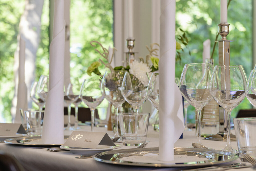 Højstrupgård - Bryllups bordopdækning med vinglas, høje lysestager, bordkort og servietter