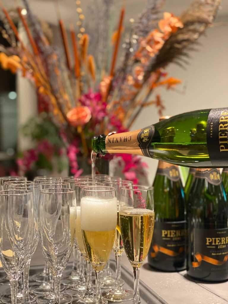 Champagne bliver fyldt på champagneglas, med vilde blomster i bagggrunden